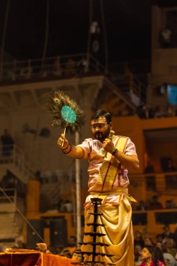 Varanasi, Uttar Pradesh, Hindistan - Kasım 2022: Ganga aarti, Dashashwamedh Ghat 'ta akşamüstü sanatan hindu ayinleriyle geleneksel elbise giymiş genç bir rahibin portresi.