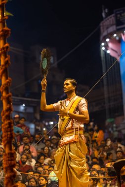 Varanasi, Uttar Pradesh, Hindistan - Kasım 2022: Ganga aarti, Dashashwamedh Ghat 'ta akşamüstü sanatan hindu ayinleriyle geleneksel elbise giymiş genç bir rahibin portresi.