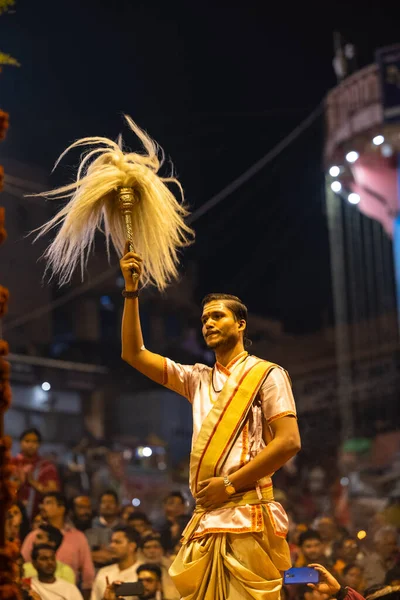 Varanasi, Uttar Pradesh, Hindistan - Kasım 2022: Ganga aarti, Dashashwamedh Ghat 'ta akşamüstü sanatan hindu ayinleriyle geleneksel elbise giymiş genç bir rahibin portresi.