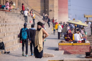 Varanasi, Uttar Pradesh, Hindistan - Kasım 2022: Varanasi şehrinde geleneksel elbise içinde nehir çetelerinin yanındaki ghat üzerindeki assi ghat 'ta tanımlanamayan Hint sadhu baba portresi.