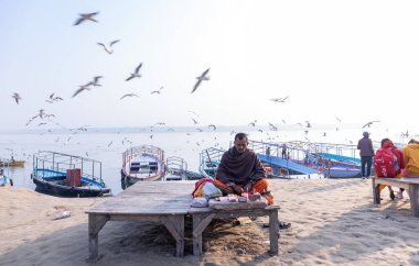 Varanasi, Uttar Pradesh, Hindistan - Kasım 2022: Varanasi şehrindeki nehir çetelerinin yakınlarındaki Assi ghat 'ta oturan kimliği belirsiz Hintli sadhu baba portresi.