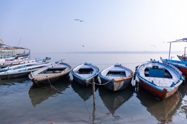 Varanasi, Uttar Pradesh, Hindistan - Kasım 2022: Nehir çeteleri yakınlarındaki sayısız ülke ahşap botlar ve tarihi malikaneler.