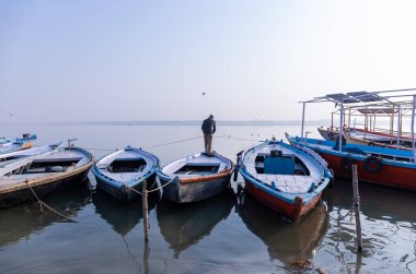 Varanasi, Uttar Pradesh, Hindistan - Kasım 2022: Nehir çeteleri yakınlarındaki sayısız ülke ahşap botlar ve tarihi malikaneler.