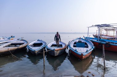Varanasi, Uttar Pradesh, Hindistan - Kasım 2022: Nehir çeteleri yakınlarındaki sayısız ülke ahşap botlar ve tarihi malikaneler.