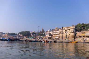 Varanasi, Uttar Pradesh, Hindistan - Kasım 2022: Antik binanın mimarisi, Tarihi Varanasi kenti, Assi ghat 'ta antik tapınaklar ve binalar mimarisi ve nehirdeki ahşap tekne.