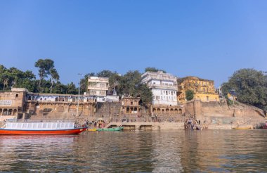 Varanasi, Uttar Pradesh, Hindistan - Kasım 2022: Antik binanın mimarisi, Tarihi Varanasi kenti, Assi ghat 'ta antik tapınaklar ve binalar mimarisi ve nehirdeki ahşap tekne.