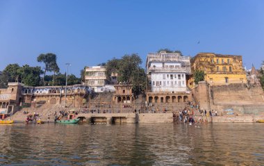 Varanasi, Uttar Pradesh, Hindistan - Kasım 2022: Antik binanın mimarisi, Tarihi Varanasi kenti, Assi ghat 'ta antik tapınaklar ve binalar mimarisi ve nehirdeki ahşap tekne.