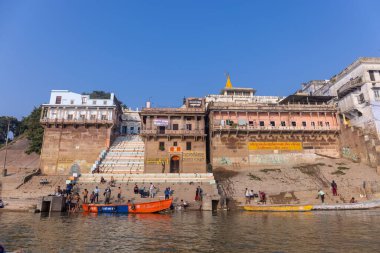 Varanasi, Uttar Pradesh, Hindistan - Kasım 2022: Antik binanın mimarisi, Tarihi Varanasi kenti, Assi ghat 'ta antik tapınaklar ve binalar mimarisi ve nehirdeki ahşap tekne.