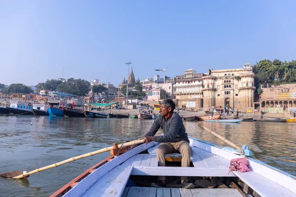 stock image Varanasi, Uttar Pradesh, India - November 2022: A view of holy ghats of Varanasi with a boatman sailing in the river ganges with old building architecture in background.