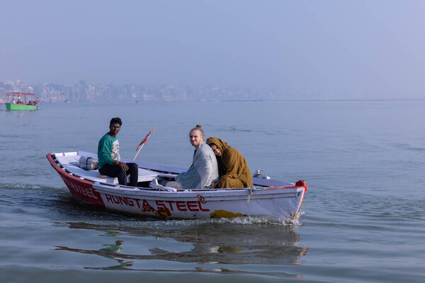 Варанаси, Уттар-Прадеш, Индия - ноябрь 2022: Туристы наслаждаются прогулкой на лодке по реке Ганг вместе со стадом морских чаек в Варанаси в течение раннего утра. Лодник, плывущий на деревянной лодке.