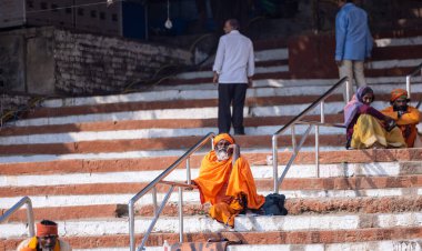Varanasi, Uttar Pradesh, Hindistan - Kasım 2022: Kimliği belirsiz Hintli sadhu baba merdivenlerde oturuyor