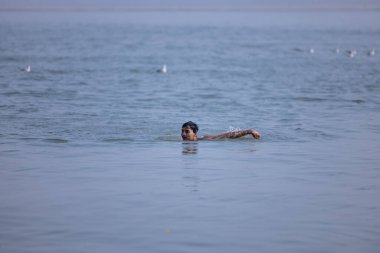 Varanasi, Uttar Pradesh, Hindistan - Kasım 2022: Kimliği belirsiz erkek portresi Hindu ayinlerini gerçekleştirmek için gün doğumunda Ganj Nehri 'ne kutsal dalış yapıyor.