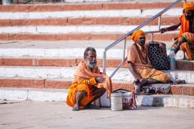 Varanasi, Uttar Pradesh, Hindistan - Kasım 2022: Kimliği belirsiz Hintli sadhu baba merdivenlerde oturuyor