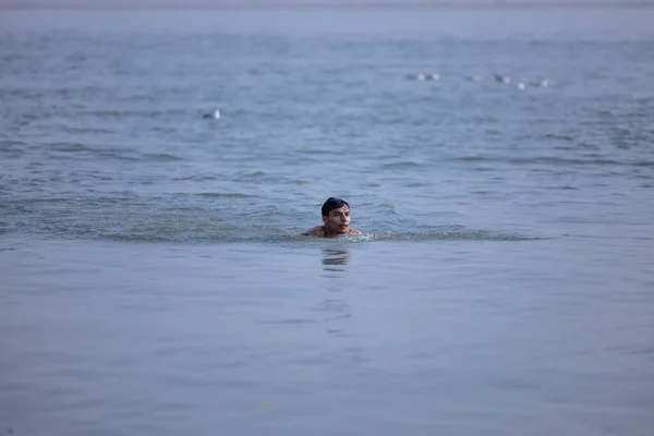 stock image Varanasi, Uttar Pradesh, India - November 2022: Portrait of unidentified male taking the holy dip in river ganges during sunrise to perform hindu rituals.