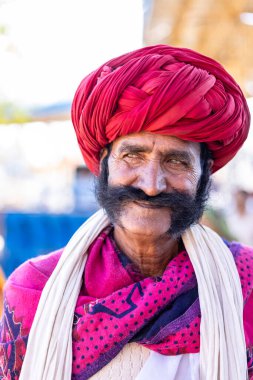 Pushkar, Rajasthan, India - November 2022: Pushkar fair, Portrait of an rajasthani old male with in white traditional dress and colorful turban at pushkar fair ground. clipart