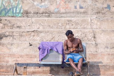 Varanasi, Uttar Pradesh, Hindistan - Kasım 2022: Varanasi şehrindeki nehir çetelerinin yakınındaki ghat 'larda kimliği belirsiz Hintli erkek portresi.