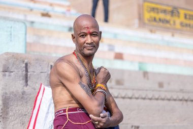 Varanasi, Uttar Pradesh, Hindistan - Kasım 2022: Kimliği belirsiz erkek portresi, gündoğumu sırasında Hint ritüeli olarak kutsal dalış yapmak için nehir çetelerinin yanında duruyordu.