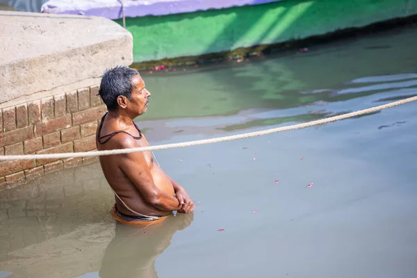 Varanasi, Uttar Pradesh, Hindistan - Kasım 2022: Kimliği belirsiz erkek portresi Hindu ayinlerini gerçekleştirmek için gün doğumunda Ganj Nehri 'ne kutsal dalış yapıyor.