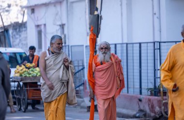 Varanasi, Uttar Pradesh, Hindistan - Kasım 2022: Varanasi şehrinde geleneksel elbise içinde nehir çeteleri yakınında yürüyen kimliği belirsiz Hint sadhu baba portresi.