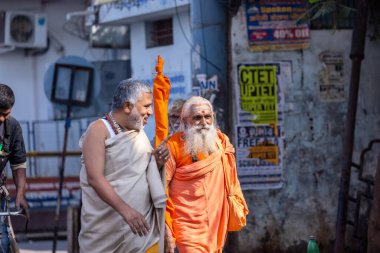 Varanasi, Uttar Pradesh, Hindistan - Kasım 2022: Varanasi şehrinde geleneksel elbise içinde nehir çeteleri yakınında yürüyen kimliği belirsiz Hint sadhu baba portresi.