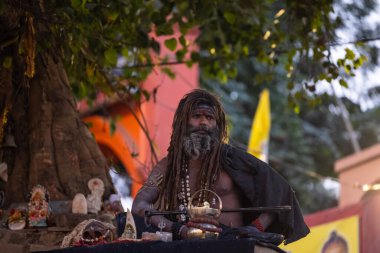 Varanasi, Uttar Pradesh, Hindistan - Kasım 2022: Varanasi şehrinde geleneksel siyah elbisesiyle nehir çetelerinin yakınındaki Assi ghat 'ta oturan tanımlanamayan Hint naga sadhu baba portresi.