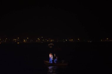 Varanasi, Uttar Pradesh, Hindistan - Kasım 2022: Turistler Varanasi 'deki nehir çetelerinde gece tekne gezintisinin keyfini çıkarıyorlar. Tekneye binen çifte odaklan..