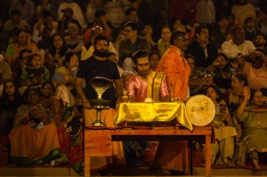 Varanasi, Uttar Pradesh, Hindistan - Kasım 2022: Ganga aarti, genç bir rahibin portresi, Assi Ghat 'ta akşam üzeri ateş ve ayinlerle geleneksel elbise giymiş nehir çetelerini icra ediyor..
