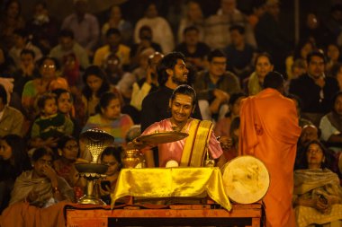 Varanasi, Uttar Pradesh, Hindistan - Kasım 2022: Ganga aarti, genç bir rahibin portresi, Assi Ghat 'ta akşam üzeri ateş ve ayinlerle geleneksel elbise giymiş nehir çetelerini icra ediyor..