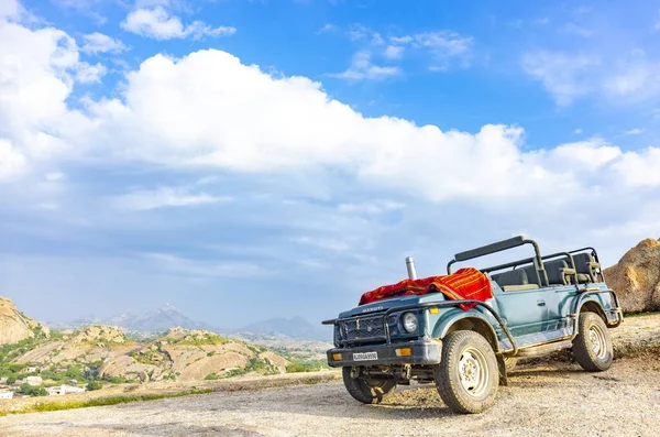 Jawai, Rajasthan, Hindistan - Eylül 2021: Hindistan 'ın Rajasthan kentindeki Aravalli dağlarının manzarası. Mavi gökyüzünün altındaki tepelerin tepesine bir safari cipi iniyor..