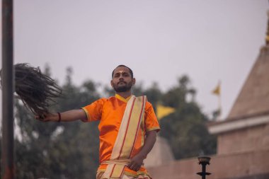 Varanasi, Uttar Pradesh, Hindistan - Kasım 2022: Ganga aarti, genç bir rahibin portresi, Assi Ghat 'ta akşam üzeri ateş ve ayinlerle geleneksel elbise giymiş nehir çetelerini icra ediyor..