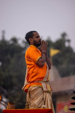 Varanasi, Uttar Pradesh, India - November 2022: Ganga aarti, Portrait of an young priest performing river ganges evening aarti at Assi Ghat in traditional dress with fire flame and rituals. clipart