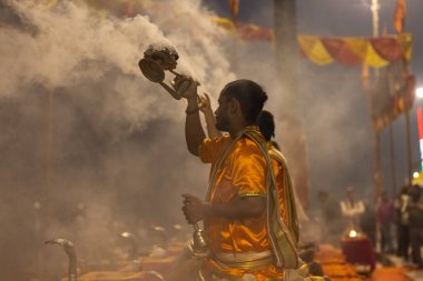 Varanasi, Uttar Pradesh, Hindistan - Kasım 2022: Ganga aarti, genç bir rahibin portresi, Assi Ghat 'ta akşam üzeri ateş ve ayinlerle geleneksel elbise giymiş nehir çetelerini icra ediyor..