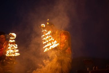 Varanasi, Uttar Pradesh, Hindistan - Kasım 2022: Ganga aarti, genç bir rahibin portresi, Assi Ghat 'ta akşam üzeri ateş ve ayinlerle geleneksel elbise giymiş nehir çetelerini icra ediyor..