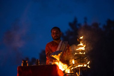 Varanasi, Uttar Pradesh, Hindistan - Kasım 2022: Ganga aarti, genç bir rahibin portresi, Assi Ghat 'ta akşam üzeri ateş ve ayinlerle geleneksel elbise giymiş nehir çetelerini icra ediyor..