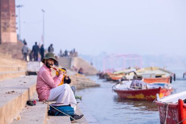 Varanasi, Uttar Pradesh, Hindistan - 20 Kasım 2022: Tanımlanamayan Hintli adam rüzgar enstrümanı çalıyor