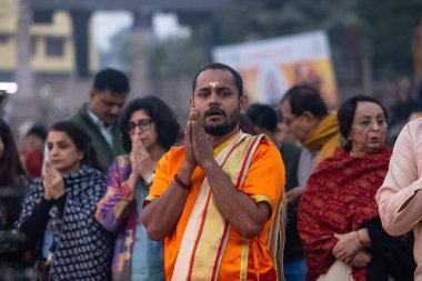 Varanasi, Uttar Pradesh, Hindistan - Kasım 2022: Ganga aarti, genç bir rahibin portresi, Assi Ghat 'ta akşam üzeri ateş ve ayinlerle geleneksel elbise giymiş nehir çetelerini icra ediyor..