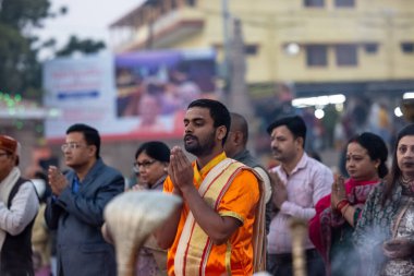 Varanasi, Uttar Pradesh, Hindistan - Kasım 2022: Ganga aarti, genç bir rahibin portresi, Assi Ghat 'ta akşam üzeri ateş ve ayinlerle geleneksel elbise giymiş nehir çetelerini icra ediyor..