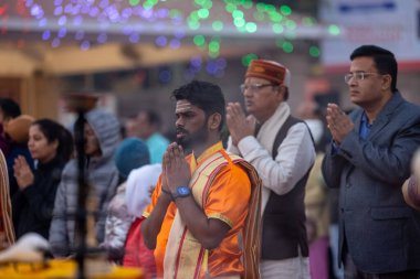 Varanasi, Uttar Pradesh, Hindistan - Kasım 2022: Ganga aarti, genç bir rahibin portresi, Assi Ghat 'ta akşam üzeri ateş ve ayinlerle geleneksel elbise giymiş nehir çetelerini icra ediyor..