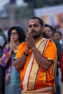 Varanasi, Uttar Pradesh, Hindistan - Kasım 2022: Ganga aarti, genç bir rahibin portresi, Assi Ghat 'ta akşam üzeri ateş ve ayinlerle geleneksel elbise giymiş nehir çetelerini icra ediyor..