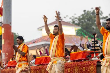 Varanasi, Uttar Pradesh, Hindistan - Kasım 2022: Ganga aarti, genç bir rahibin portresi, Assi Ghat 'ta akşam üzeri ateş ve ayinlerle geleneksel elbise giymiş nehir çetelerini icra ediyor..