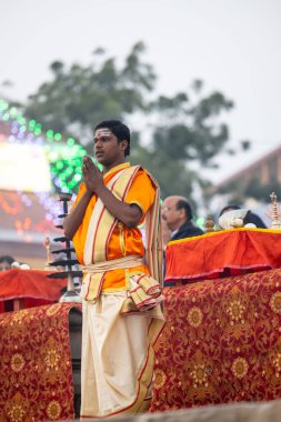 Varanasi, Uttar Pradesh, Hindistan - Kasım 2022: Ganga aarti, genç bir rahibin portresi, Assi Ghat 'ta akşam üzeri ateş ve ayinlerle geleneksel elbise giymiş nehir çetelerini icra ediyor..