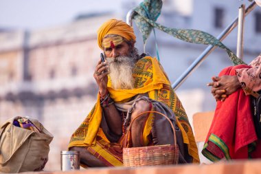 Varanasi, Uttar Pradesh, Hindistan - 20 Kasım 2022: Varanasi şehrinde geleneksel elbise içinde nehir çetelerinin yakınlarındaki Kedar ghat merdivenlerinde kimliği belirlenemeyen kutsal Hint sadhu 'nun portresi