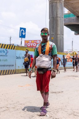 Gaziabad, Uttar Pradesh, Hindistan - 24 Temmuz 2022: Hindu hacı portresi Muson zamanında Lord Shiv 'e ibadet etmek ve nehir çetelerinin kutsal suyunu taşımak için çıplak ayakla kanwar yatra yapıyor.