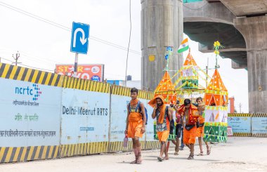 Gaziabad, Uttar Pradesh, Hindistan - 24 Temmuz 2022: Hindu hacı portresi Muson zamanında Lord Shiv 'e ibadet etmek ve nehir çetelerinin kutsal suyunu taşımak için çıplak ayakla kanwar yatra yapıyor.