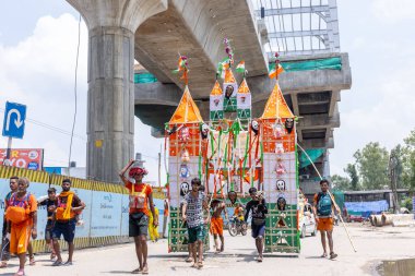 Gaziabad, Uttar Pradesh, Hindistan - 24 Temmuz 2022: Hindu hacı portresi Muson zamanında Lord Shiv 'e ibadet etmek ve nehir çetelerinin kutsal suyunu taşımak için çıplak ayakla kanwar yatra yapıyor.