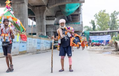 Gaziabad, Uttar Pradesh, Hindistan - 24 Temmuz 2022: Hindu hacı portresi Muson zamanında Lord Shiv 'e ibadet etmek ve nehir çetelerinin kutsal suyunu taşımak için çıplak ayakla kanwar yatra yapıyor.