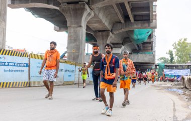 Gaziabad, Uttar Pradesh, Hindistan - 24 Temmuz 2022: Hindu hacı portresi Muson zamanında Lord Shiv 'e ibadet etmek ve nehir çetelerinin kutsal suyunu taşımak için çıplak ayakla kanwar yatra yapıyor.