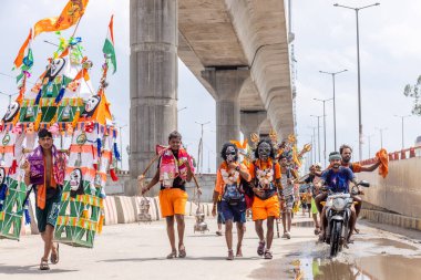 Gaziabad, Uttar Pradesh, Hindistan - 24 Temmuz 2022: Hindu hacı portresi Muson zamanında Lord Shiv 'e ibadet etmek ve nehir çetelerinin kutsal suyunu taşımak için çıplak ayakla kanwar yatra yapıyor.