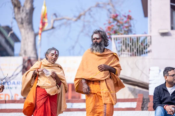 stock image Varanasi, Uttar Pradesh, India - November 20 2022: Portrait of Unidentified Indian holy sadhu male and female walking at kedar ghat near river ganges in varanasi city in traditional saffron dress.