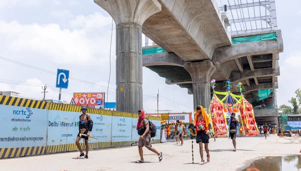 Gaziabad, Uttar Pradesh, Hindistan - 24 Temmuz 2022: Hindu hacı portresi Muson zamanında Lord Shiv 'e ibadet etmek ve nehir çetelerinin kutsal suyunu taşımak için çıplak ayakla kanwar yatra yapıyor.